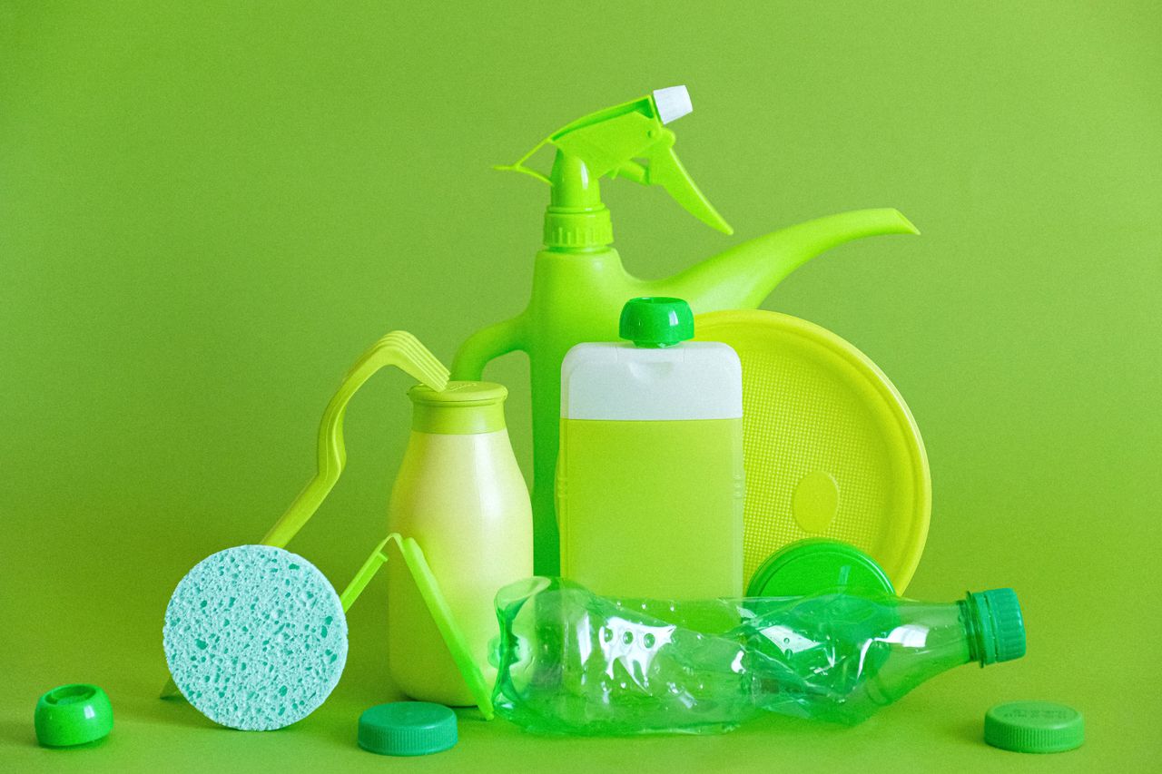 Monochrome green bottles and containers for liquids or gel with plastic bottle and lids on green background